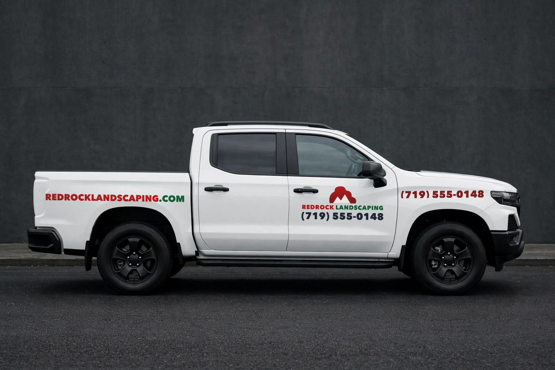 White pickup with a fictional landscaping decal set: door logo, phone number and services